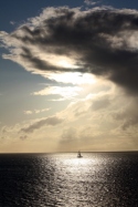 A sailboat sail towards the horizon and a ocean storm